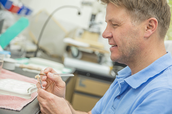 Zahntechniker bei der Präzisionsarbeit im praxiseigenen Dentallabor